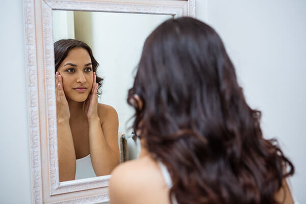 Woman looking into mirror after Diamond Glow Facial 